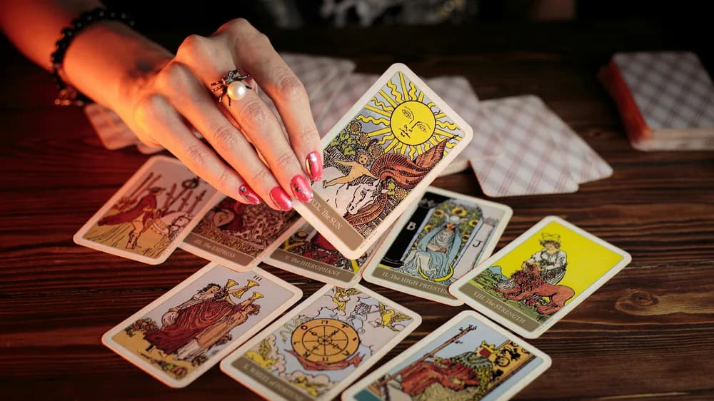 Mão feminina revelando cartas de tarot em consulta sobre sentimentos de amor